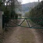 Servitude de passage privé : comment faire respecter le droit de passage sur un chemin commun Barrière métallique verte fermant un chemin de terre